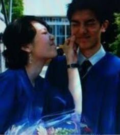 a man and woman standing next to each other in graduation gowns, one is kissing the other's cheek