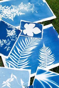 blue and white paper cut outs with leaves on them sitting in the grass next to each other