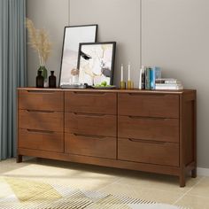 a wooden dresser with two pictures on top and other items sitting on the bottom shelf