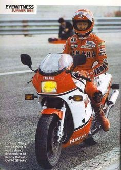 a man riding on the back of an orange and white motorbike in a race track