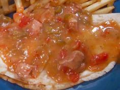 a blue plate topped with french fries and a hot dog covered in condiments