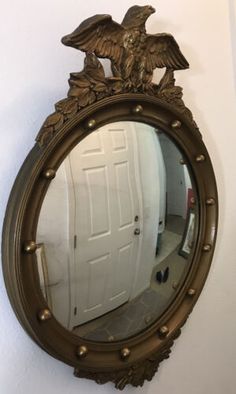 a mirror hanging on the wall with an eagle design in it's center,