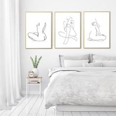 a white bedroom with three framed drawings on the wall