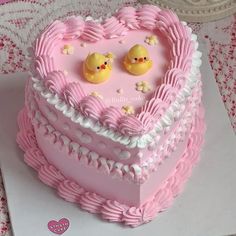 a pink heart shaped cake with two little chicks on it's top and hearts in the middle