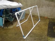 a white bicycle frame sitting next to a pile of blue chairs and bags on the ground