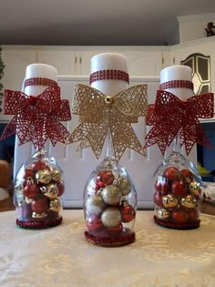 three glass vases with ornaments in them on a table