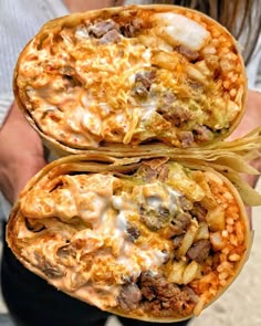 two burritos with meat and cheese on them are held up in front of the camera