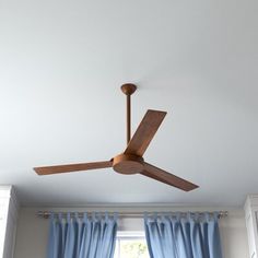 a ceiling fan in a room with blue curtains