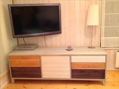 a flat screen tv sitting on top of a wooden cabinet in a living room next to a lamp