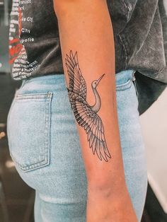 a woman's arm with a bird tattoo on the left side of her arm