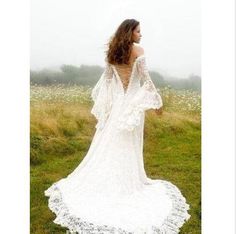 a woman in a white dress standing on top of a lush green field