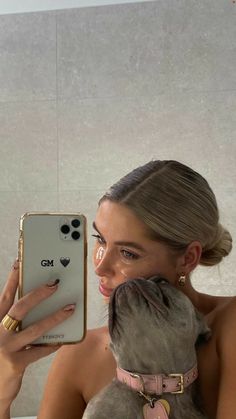 a woman taking a selfie with her cell phone while holding a dog in front of her