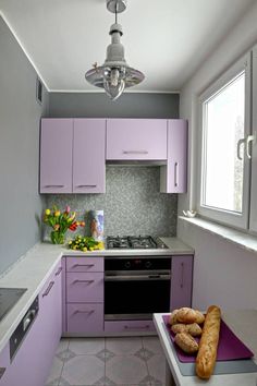 a kitchen with purple cabinets and white counter tops is pictured in this image, there are croissants on the counter