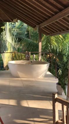 a large white bath tub sitting on top of a cement floor next to palm trees