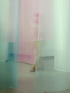 a blurry photo of a person standing in front of a pink and blue curtain