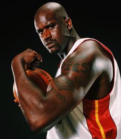 a man holding a basketball in his right hand and posing for the camera with one arm wrapped around him