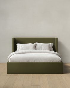 a bed with white sheets and pillows on top of it in front of a wall