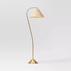 a gold floor lamp with a white shade on the base and a light bulb attached to it