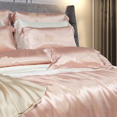 a bed with pink comforters and pillows on it's headboard in a bedroom