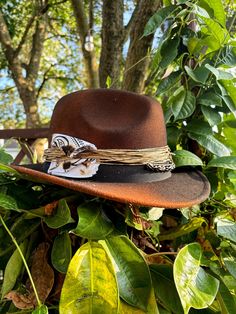 This custom fedora is titled "The Florist" and features personalized distressing and accessories that can be found on the hat. The title, "The Florist" comes from the dried flower that is attached to side of the fedora. The hat also contains burned twine, a bandana, black/white beads and black accents throughout. The fedora is a one-size-fits-most, but specifically is measured as a L/60. Please do keep that in mind before purchasing, thanks! Don't miss out on the opportunity of owning this one-of-one piece, it will never be recreated again! Rustic Adjustable Brown Top Hat, Vintage Distressed Hat For Western-themed Events, Rustic Distressed Brown Fedora Hat, Vintage Distressed Brown Hat For Western-themed Events, Vintage Handmade Hat Band For Western-themed Events, Vintage Handmade Hats For Western-themed Events, Vintage Handmade Hat For Western-themed Events, Brown Hat Bands For Western-themed Events, Unique Brown Hat Bands For Western-themed Events