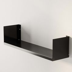 a black shelf mounted to the side of a wall