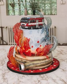 a multi - tiered cake decorated with firetrucks and flames on a table