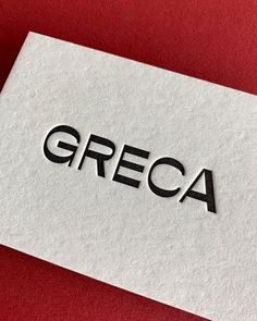 a piece of paper with the word greca on it sitting on a red surface