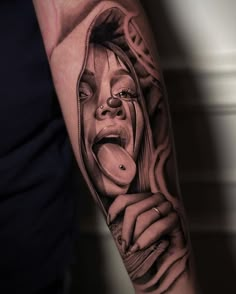 a woman sticking her tongue out with an open mouth tattoo on the left upper arm