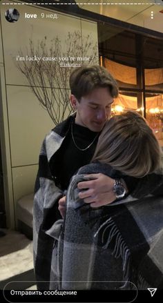 two people embracing each other in front of a building