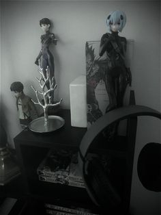 two figurines are sitting on top of a desk next to a mirror and lamp