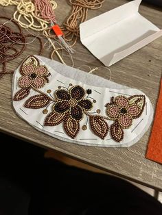 an assortment of beadwork and craft supplies on a wooden table with orange thread