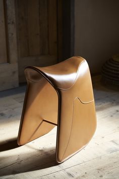 a brown leather chair sitting on top of a wooden floor next to a wall and door