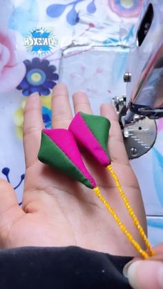 someone is using a sewing machine to sew something pink and green in their hand