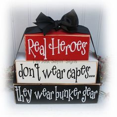 three wooden signs that say real hero, don't wear capes and they wear bunker gear