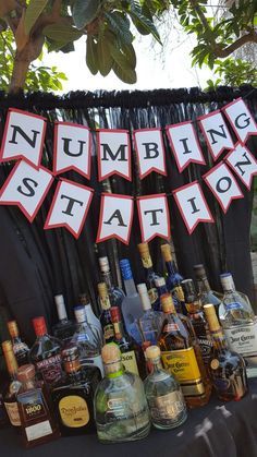 there are many liquor bottles on the table with bunting signs in front of them