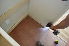 a person using a power drill on the floor in front of a wall and door