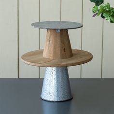 three tiered wooden cake stand on top of a table next to a potted plant