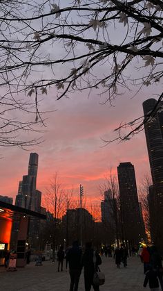 people are walking around in the city at sunset or dawn with tall buildings behind them