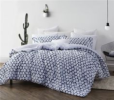 a bed with white and blue comforters in a room next to a cacti