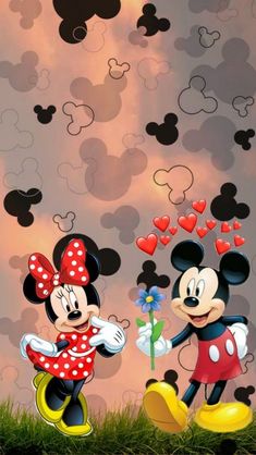 two mickey and minnie mouses standing in front of a wall with hearts on it