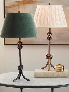 two lamps sitting on top of a table next to a book and a lamp shade