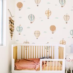 a baby's room with hot air balloons on the wall and a crib