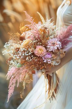 a bride holding a bouquet of flowers in her hand with the sun shining through it