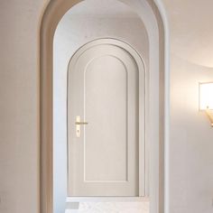 an arched doorway leading into a bathroom with white walls and marble counter tops, along with a sink