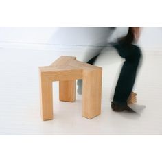 a person riding a skateboard past a small wooden table on the white tiled floor