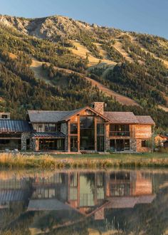 a large house sitting in the middle of a lush green field next to a lake