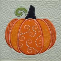 an orange and white quilted pumpkin sitting on top of a piece of paper with the word