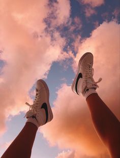 two people standing in the sky with their feet up and one person wearing white sneakers