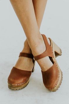 Complete any of your favorite outfits with the Abba Clogs! These genuine leather beauties feature an enclosed toe and adjustable ankle strap to provide you the everyday comfort you deserve. The wooden platform heel, stitched detailing, and bold color options are sure to make a statement this season! Handmade in Sweden with Swedish Alderwood and Italian leather *FINAL SALE* Mia Clogs Outfit, Mia Clogs, Black Luggage, Buffalo Plaid Dress, Clog Shoes, Clog Heels, Saddle Brown, Wooden Heel, Leather Clogs