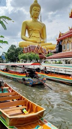 boats are lined up in front of a large buddha statue